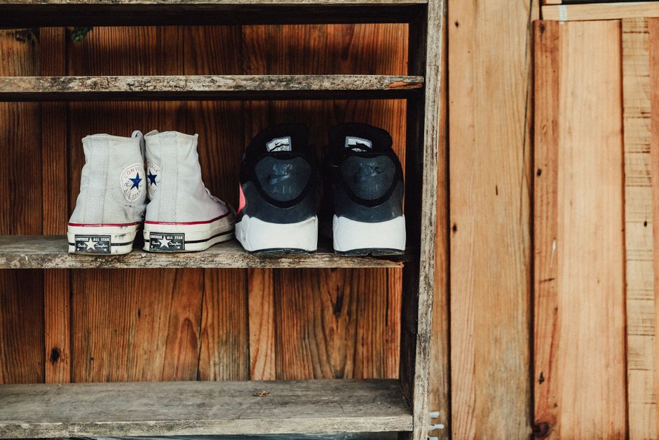 A rustic wooden shelf displaying Converse All Star and Nike shoes, perfect for fashion and vintage themes.